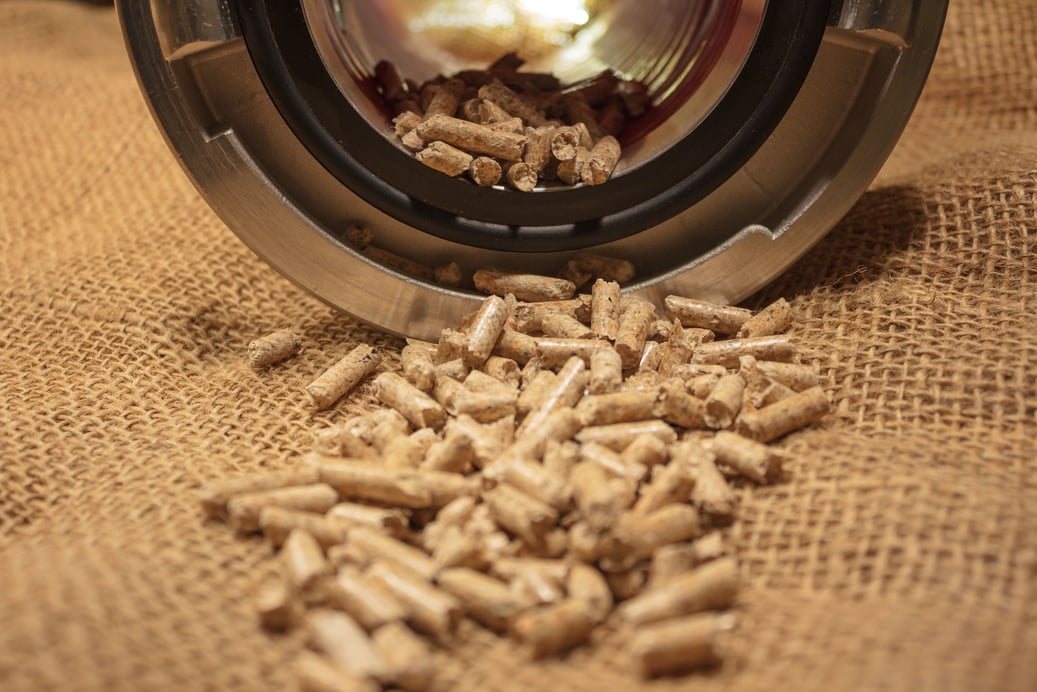 Close-up shot of fuel pellets with a background of a metal pot resting on a knitted brown fabric